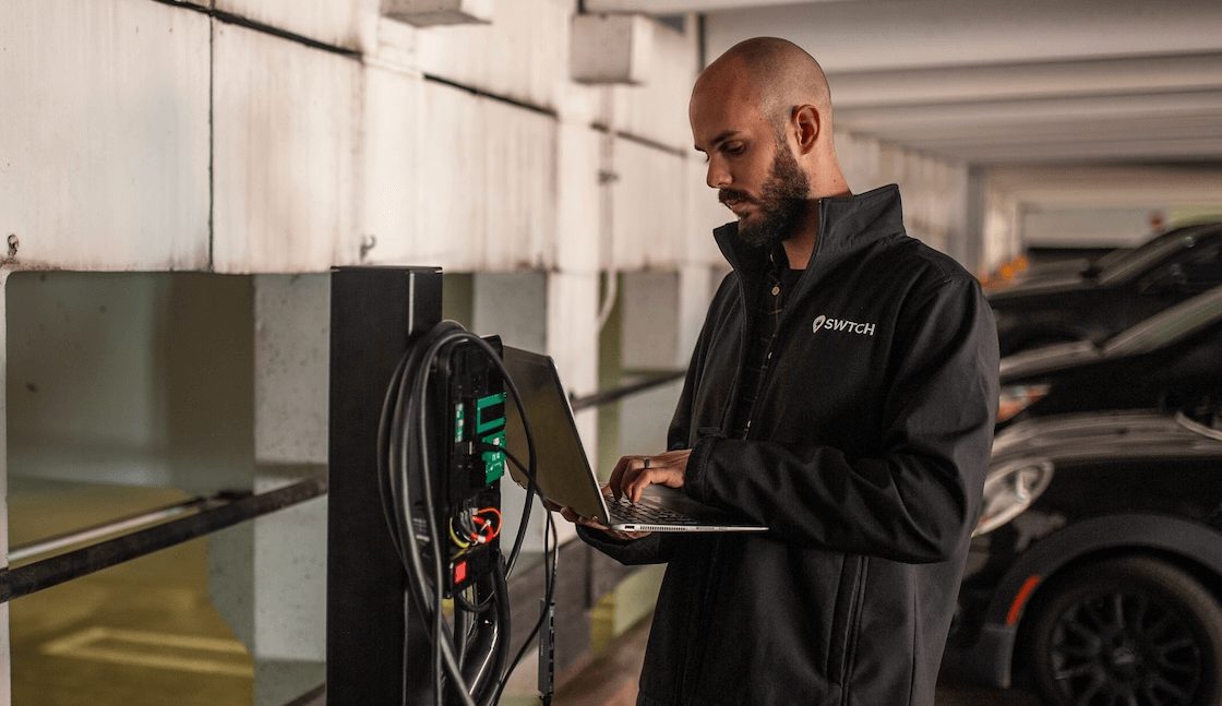 An image of someone inspecting an EV charger to ensure it is reliable.