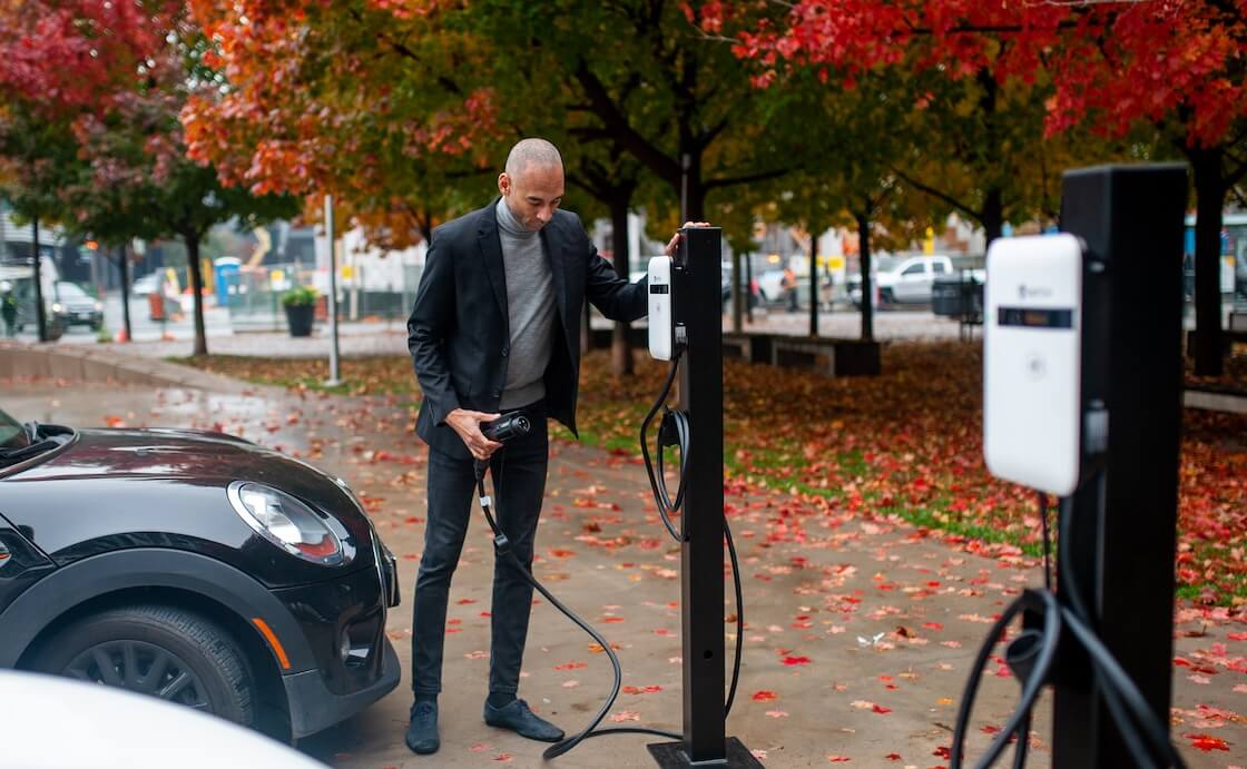 Shows a man plugging his car into his EV charger